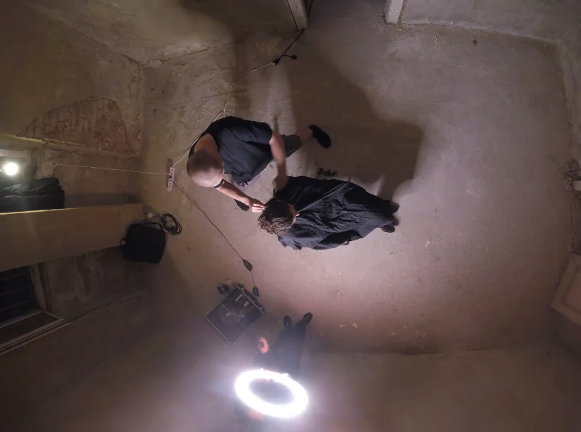 Overhead surveillance-camera still of a haircut being given in a vacant room lit by a ring light