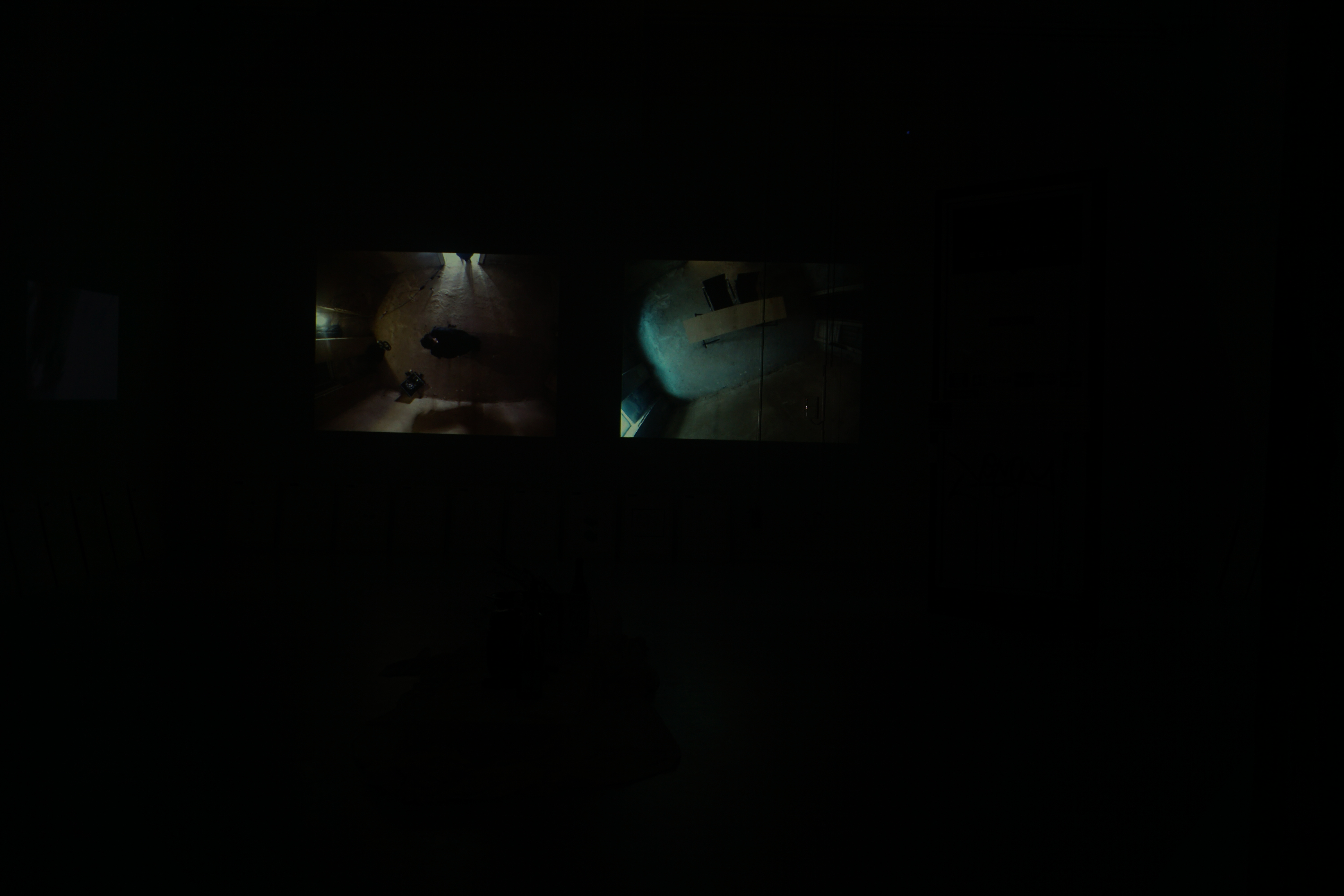 Darkened room with the two channels of the video installation glowing on the wall