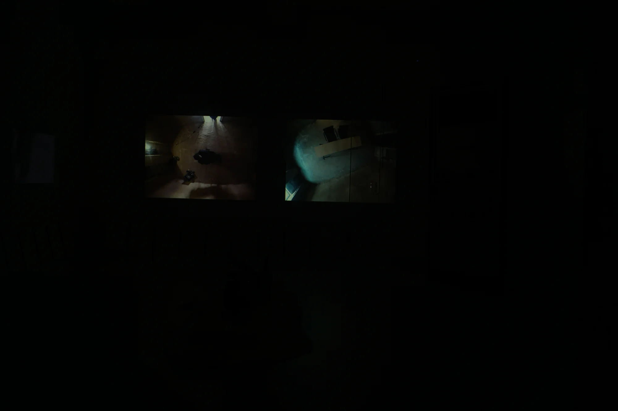 Darkened room with the two channels of the video installation glowing on the wall